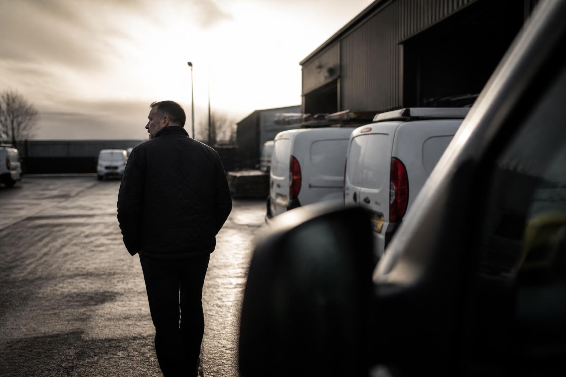 An owner walking through a commercial depot yard at first light